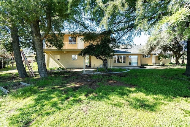 view of front facade with stucco siding, a patio area, and a front yard