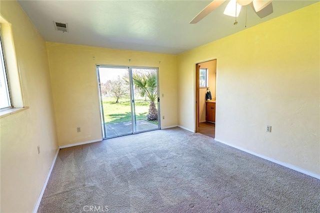 carpeted empty room with baseboards, visible vents, and a ceiling fan