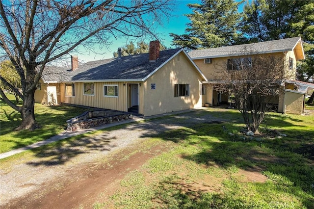 view of front facade featuring driveway, a chimney, and a front lawn