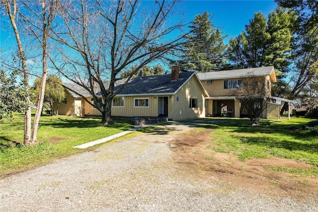 view of front facade with a front yard, driveway, and a chimney