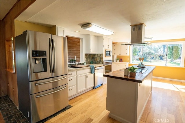 kitchen with stainless steel appliances, white cabinets, a sink, and island range hood