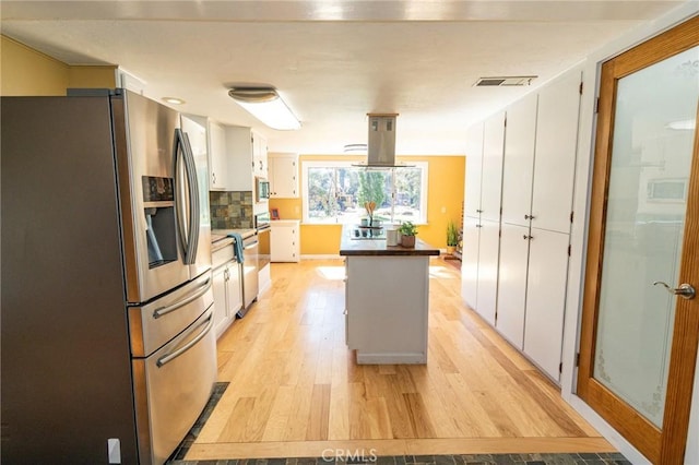 kitchen with light wood-style flooring, visible vents, appliances with stainless steel finishes, tasteful backsplash, and island exhaust hood