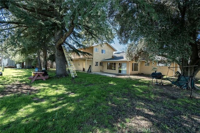 back of property with a patio area, a lawn, and stucco siding