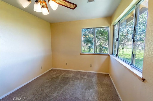 carpeted spare room featuring ceiling fan, visible vents, and baseboards