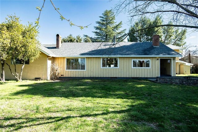 rear view of house with a yard, a chimney, and board and batten siding