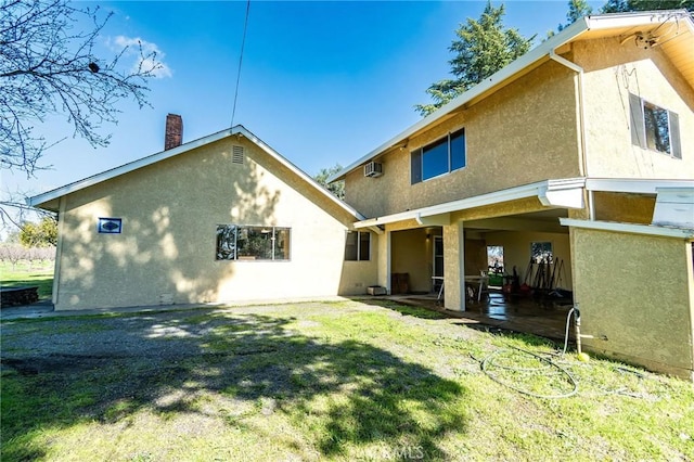 rear view of house with a patio, a yard, a wall mounted AC, and stucco siding