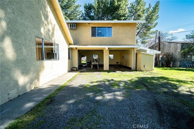 rear view of property featuring a lawn and stucco siding