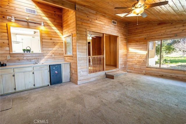 interior space featuring lofted ceiling, wooden ceiling, visible vents, and wooden walls