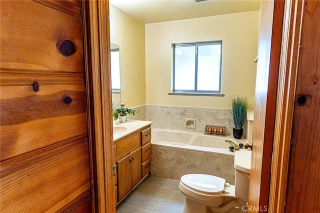 bathroom with toilet, a garden tub, and vanity