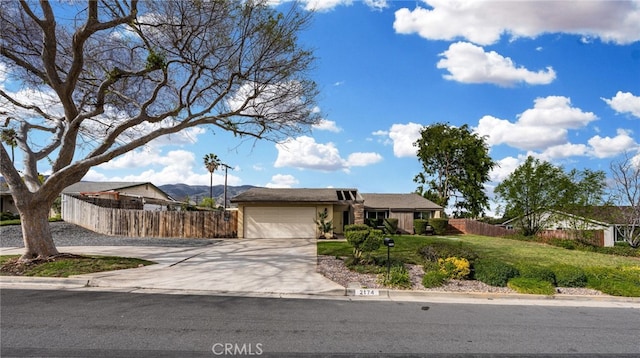 ranch-style house featuring concrete driveway, fence, a garage, and a front lawn