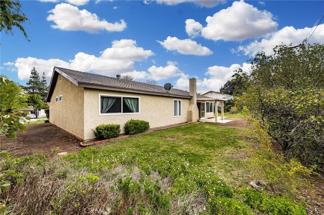 rear view of property with a patio area, stucco siding, and a yard