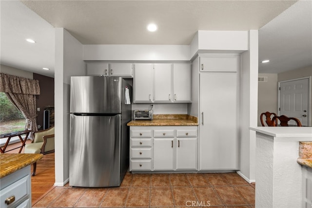 kitchen featuring light tile patterned floors, recessed lighting, visible vents, and freestanding refrigerator