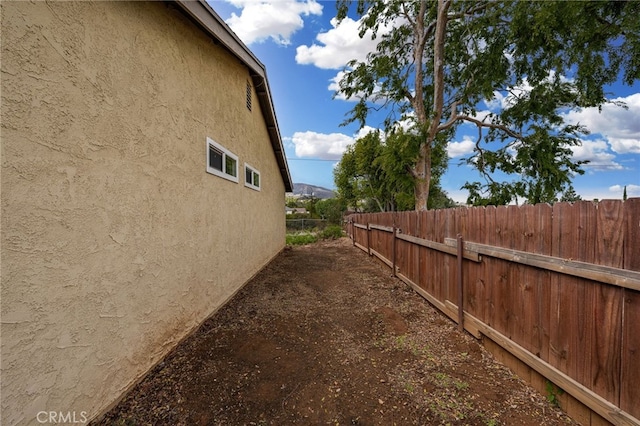 view of side of home with fence and stucco siding