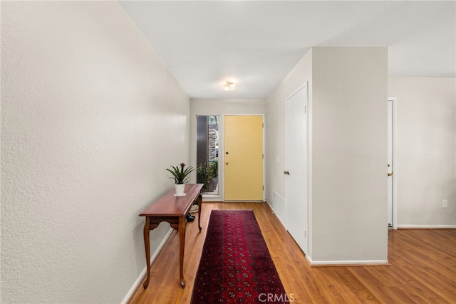 doorway to outside featuring baseboards and light wood-style floors