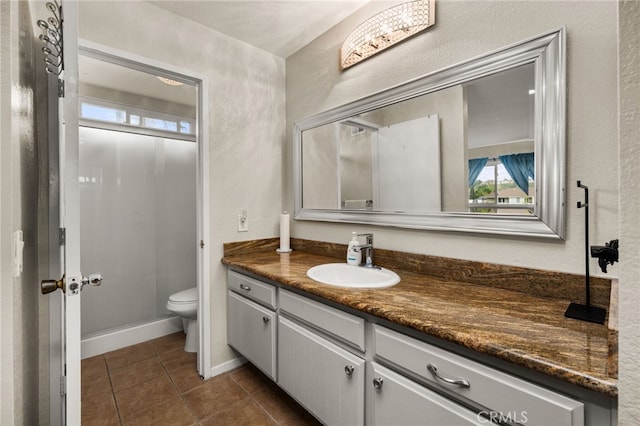 bathroom with tile patterned flooring, baseboards, toilet, a textured wall, and vanity