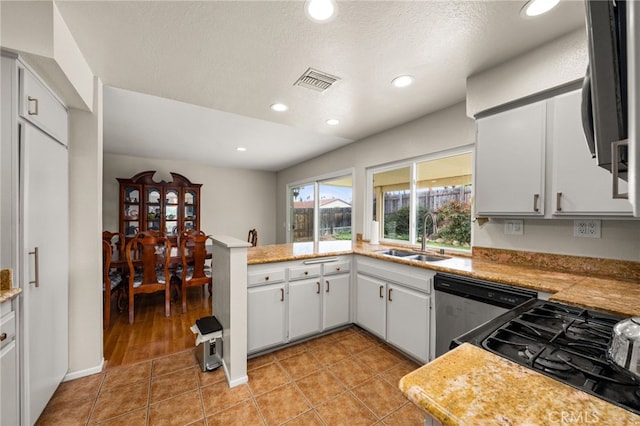 kitchen with light tile patterned floors, visible vents, a sink, light countertops, and dishwasher