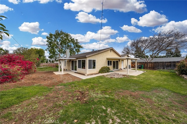 back of house with a fenced backyard, stucco siding, a yard, and a patio