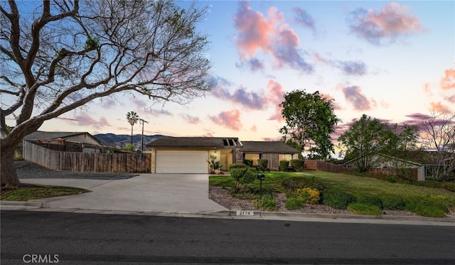 ranch-style home with driveway, an attached garage, a front lawn, and fence