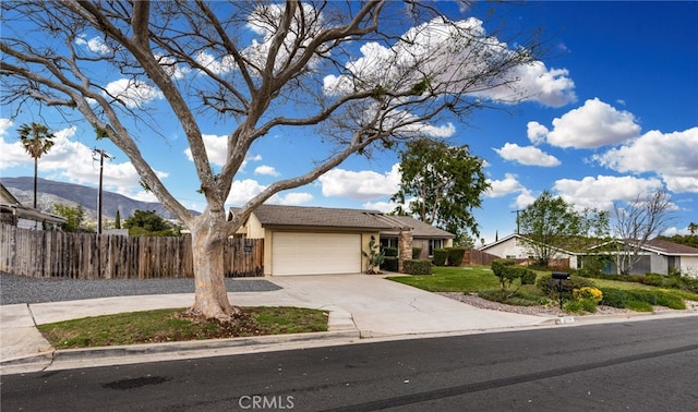 single story home with stucco siding, fence, a mountain view, concrete driveway, and a garage