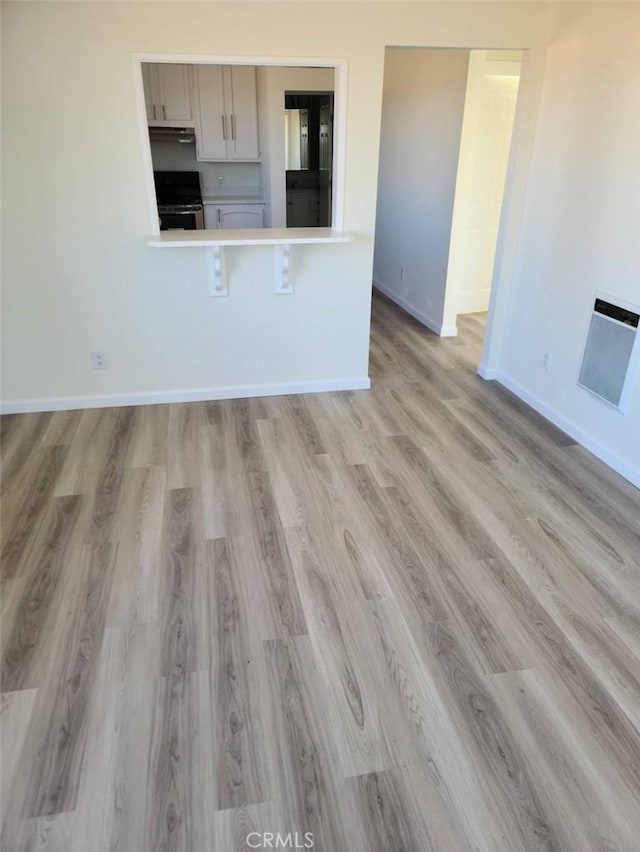 kitchen with light wood-style flooring, under cabinet range hood, baseboards, electric stove, and light countertops