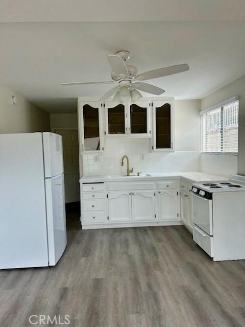 kitchen featuring white appliances, white cabinetry, a sink, and wood finished floors