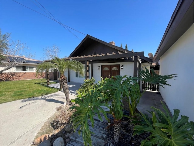 view of front of home with a front yard, french doors, and stucco siding