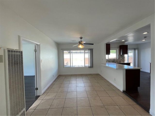 interior space featuring light tile patterned floors, ceiling fan, a peninsula, a sink, and a heating unit