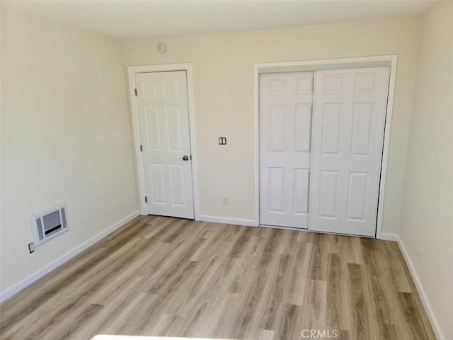 unfurnished bedroom with a closet, light wood finished floors, and baseboards