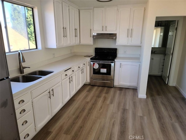 kitchen with wood finished floors, stainless steel range with electric cooktop, under cabinet range hood, white cabinetry, and a sink