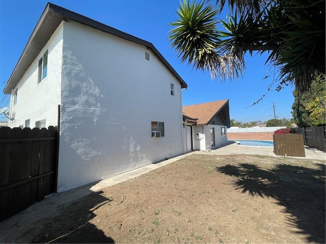 view of side of home with fence, a fenced in pool, and stucco siding