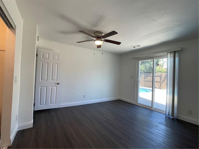 empty room with visible vents, dark wood finished floors, a textured ceiling, and baseboards