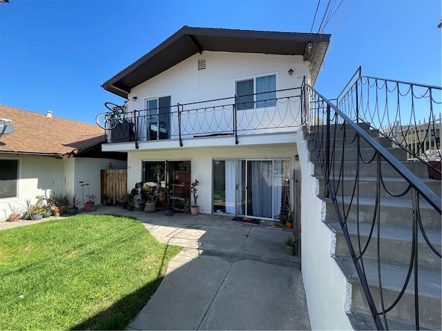 back of house featuring a patio area, a lawn, a balcony, and stucco siding