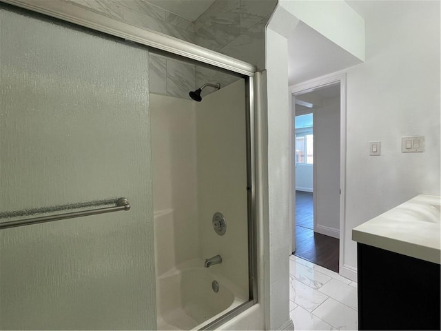 bathroom featuring marble finish floor, combined bath / shower with glass door, vanity, and baseboards