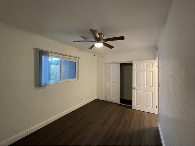 unfurnished bedroom with ceiling fan, dark wood-type flooring, visible vents, baseboards, and a closet