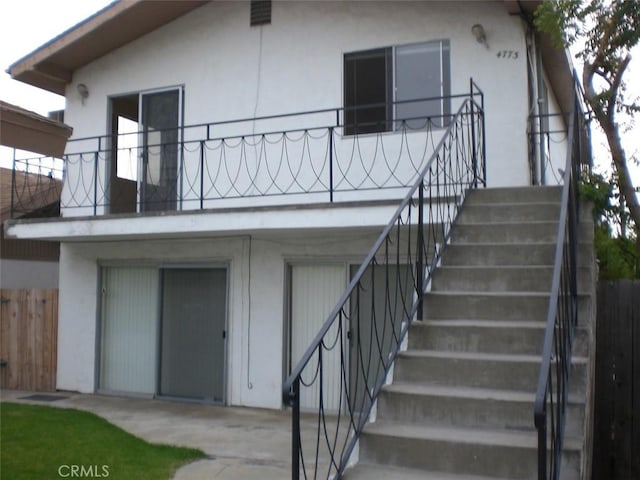 back of property with stairs, fence, and stucco siding