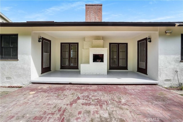 property entrance with stucco siding, a chimney, brick siding, and crawl space