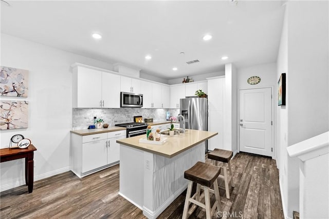 kitchen with appliances with stainless steel finishes, dark wood-style flooring, visible vents, and tasteful backsplash