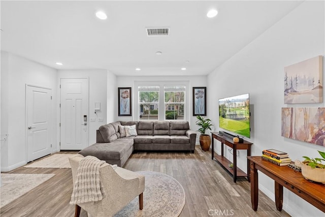 living room with baseboards, light wood-type flooring, visible vents, and recessed lighting