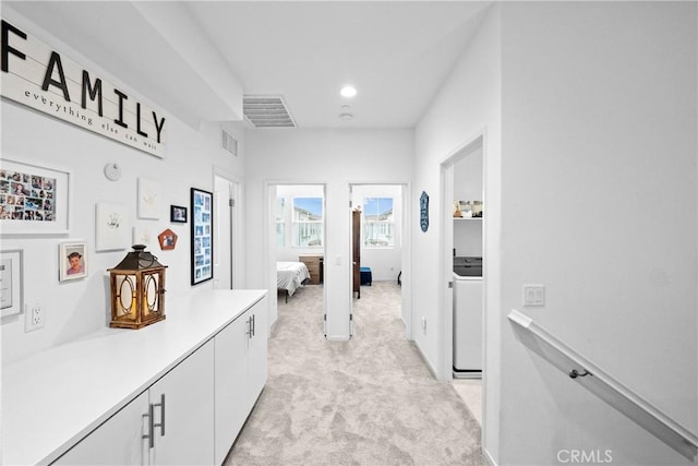 hall featuring washer / dryer, light colored carpet, visible vents, and recessed lighting