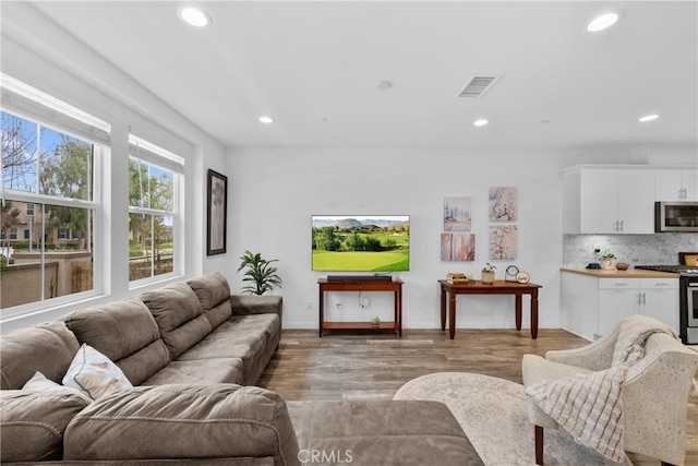 living area featuring light wood-type flooring, visible vents, baseboards, and recessed lighting