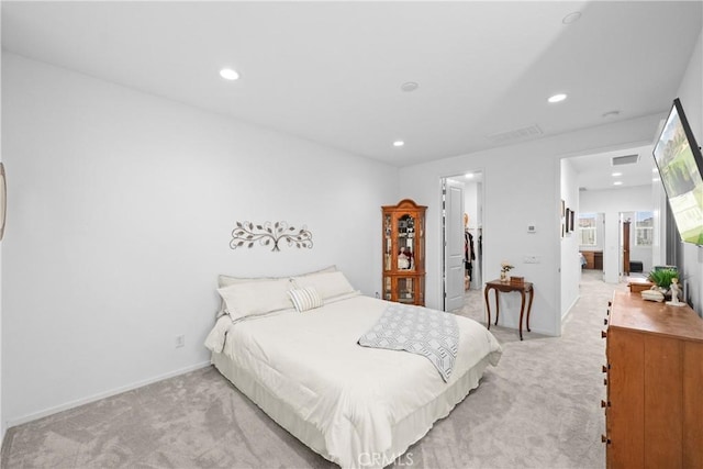 bedroom featuring recessed lighting, baseboards, a walk in closet, and light colored carpet