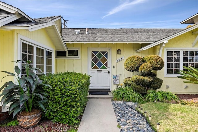 entrance to property featuring roof with shingles