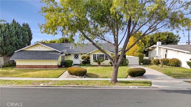 ranch-style house featuring a front lawn and roof with shingles