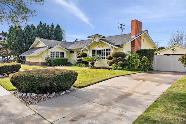 view of front of home with a front lawn, a chimney, and a gate