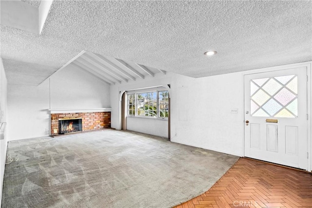 unfurnished living room with lofted ceiling, a textured ceiling, a brick fireplace, and carpet flooring