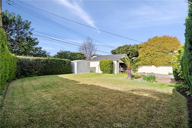 view of yard featuring a storage unit, an outbuilding, and a fenced backyard