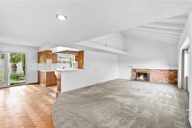 unfurnished living room featuring a brick fireplace, a textured ceiling, and lofted ceiling