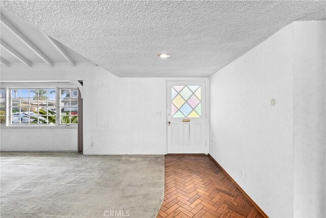 unfurnished room featuring beam ceiling and a textured ceiling