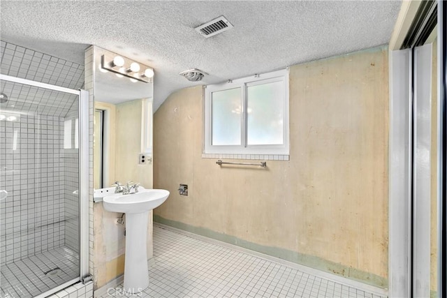 bathroom featuring tile patterned flooring, visible vents, a shower stall, baseboards, and a textured ceiling