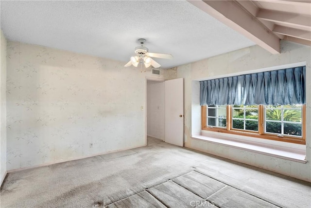 spare room featuring a textured ceiling, ceiling fan, carpet flooring, and wallpapered walls